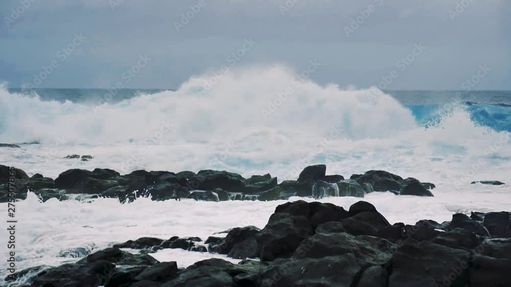 Incredible low angle view of waves pounding the rocky coast of Tenerife in slow motion. Blue Atlantic Ocean surf slamming against the rocks along the shoreline sending water and spray into the air. Incredible low angle view of waves pounding the rocky coast of Tenerife in slow motion. Blue Atlantic Ocean surf slamming against the rocks along the shoreline sending water and spray into the air.