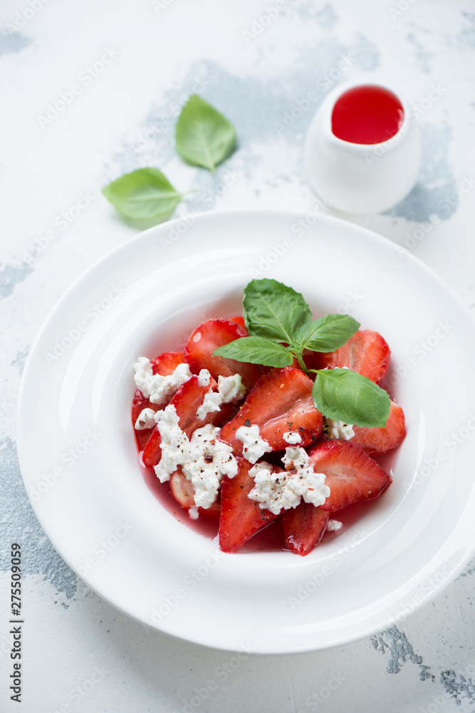 White plate with strawberry dessert, elevated view over white concrete background, vertical shot