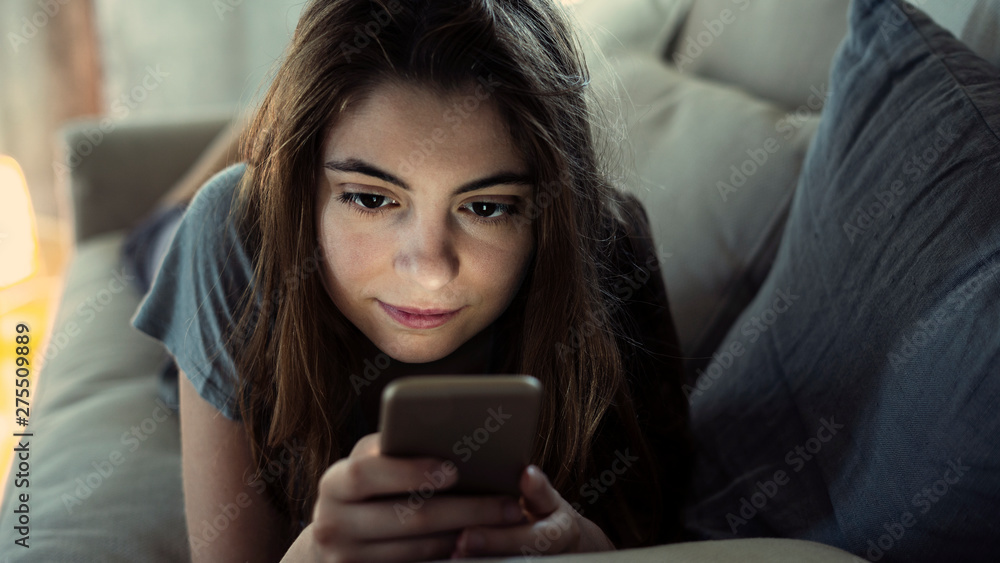 Young girl using her mobile phone on sofa Young girl using her mobile phone on sofa
