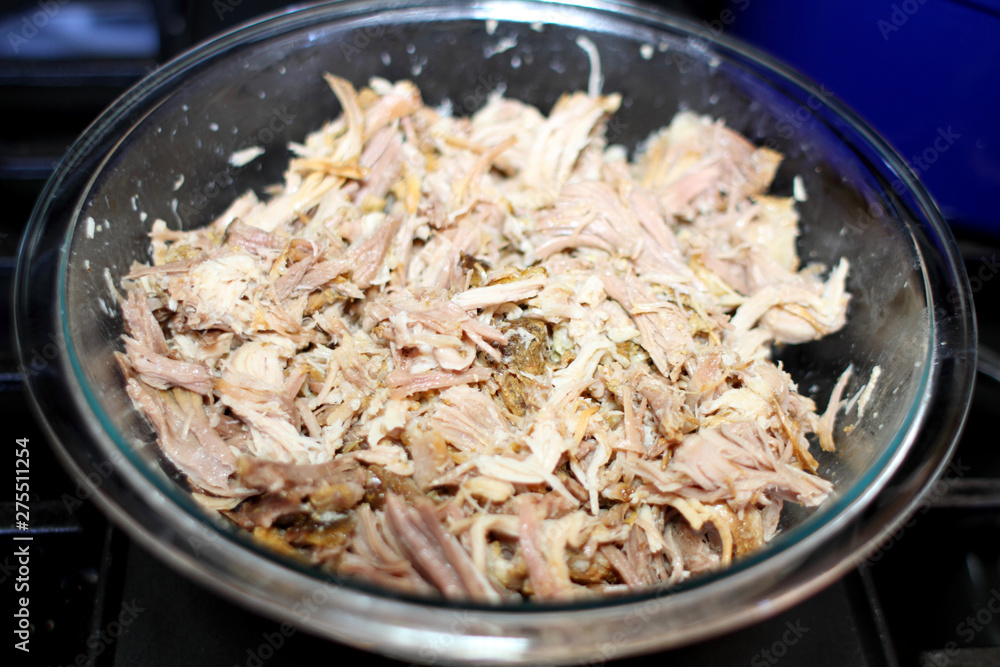 Delicious roasted pulled pork in a glass bowl on the stove top in a home kitchen. Delicious roasted pulled pork in a glass bowl on the stove top in a home kitchen.