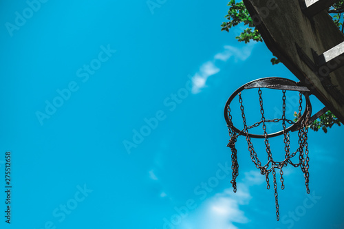 Metallic basketball hoop with chain placed on a wooden board outdoor with blue sky in background     Fun and competitive activity equipment with copy space