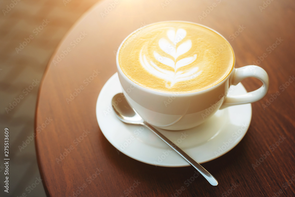 Freshly brewed cappuccino in a cup of white color on a wooden table in the morning during breakfast
