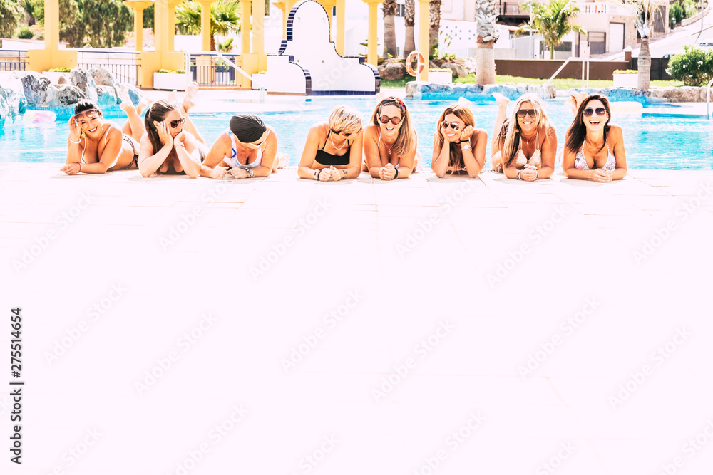 Group of cheerful happy people lay down at the pool on a white floor - friendship and young women on vacation concept - friends having fun together during summer holiday vacation