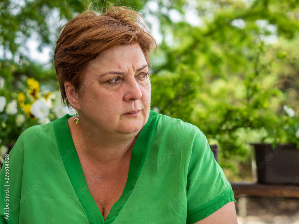 A middle-aged woman in a green shirt resting in a city Park A middle-aged woman in a green shirt resting in a city Park