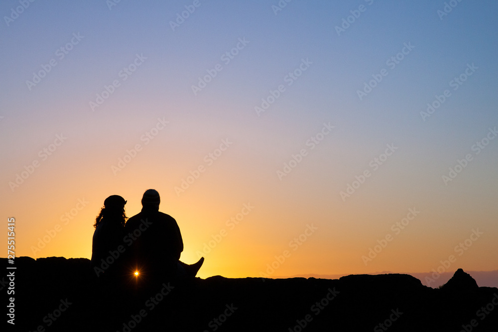 A couple watches a sunset from a viewpoint along Highway 101.