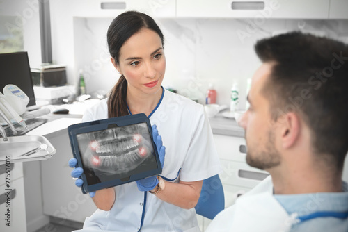 Photos Female dentist showing teeth x-ray on tablet