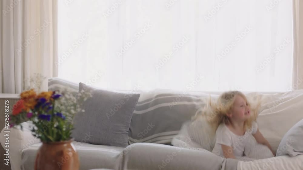 beautiful little girl jumping on sofa dancing having fun child in playful mood enjoying weekend morning at home beautiful little girl jumping on sofa dancing having fun child in playful mood enjoying weekend morning at home