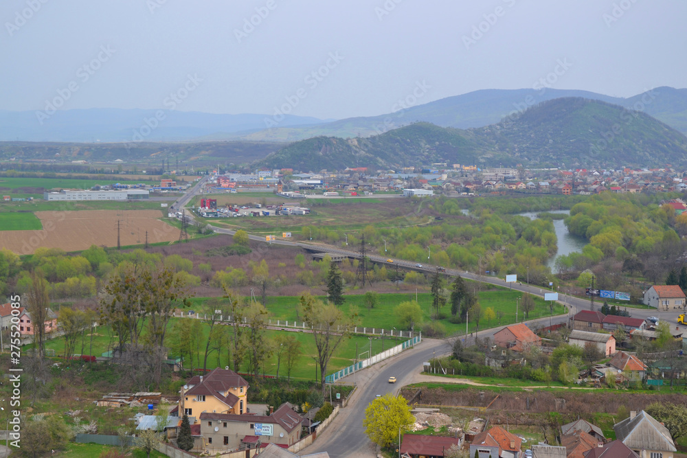 Panoramic view of the city at the foot of the mountains at dawn. Forests, houses and river