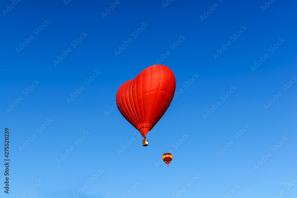 Fototapeta premium Red heart shaped balloon on the background blue sky.
