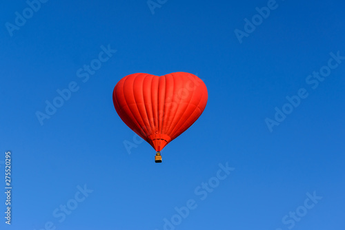 Red heart shaped balloon on the background blue sky.