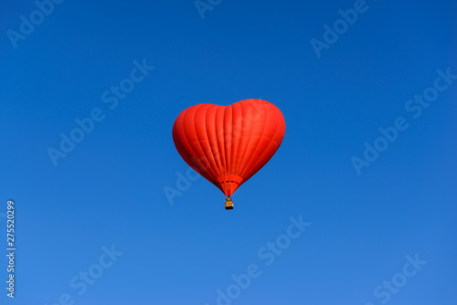 Red heart shaped balloon on the background blue sky. © 7707601