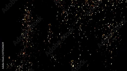 golden sparkles goes up on black background, slow motion
