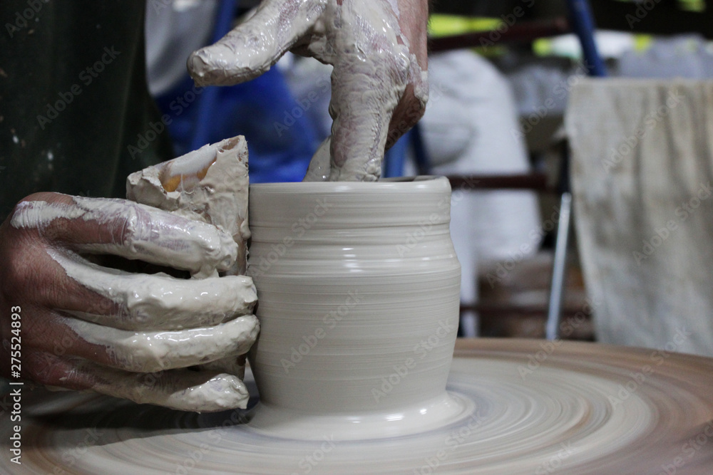 a craftsman with 13 years of experience unscrews a cylinder on a potter's wheel - the fundamental form of any ceramic product and fingers shaped it a pot. correct hand setting.