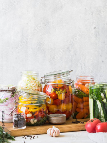 Cooking pickled vegetables. Salting various vegetables in glass jars for long-term storage. Preserves vegetables in glass jars. Variety fermented green vegetables on wood board photo