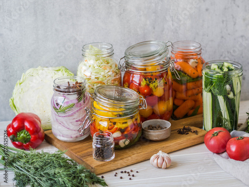 Cooking pickled vegetables. Salting various vegetables in glass jars for long-term storage. Preserves vegetables in glass jars. Variety fermented green vegetables on wood board photo