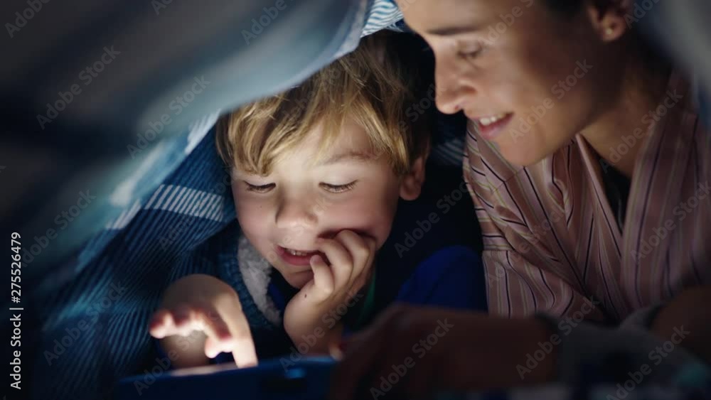 mother and child using tablet computer under blanket playing games on touchscreen technology little boy having fun before bedtime mother and child using tablet computer under blanket playing games on touchscreen technology little boy having fun before bedtime