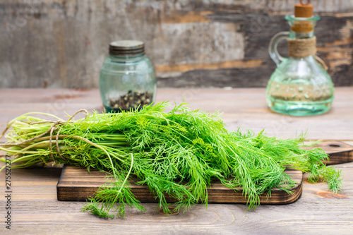 A bunch of fresh dill on a cutting board on a wooden table. Fragrant seasoning in rustic style