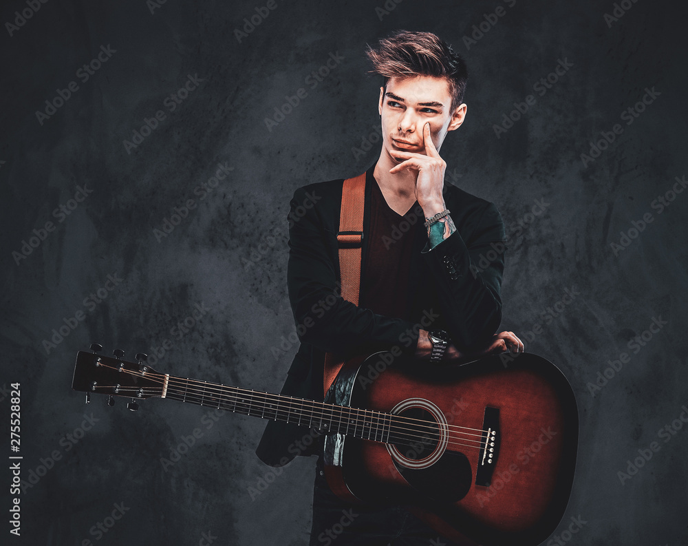 Young attractive man is playing acoustic guitar at studio while posing for  photographer. Stock Photo | Adobe Stock