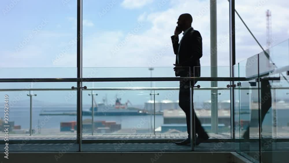 businessman using smartphone having phone call corporate executive talking to international client discussing work for shipping company on mobile phone in office lobby with view of harbor port businessman using smartphone having phone call corporate executive talking to international client discussing work for shipping company on mobile phone in office lobby with view of harbor port