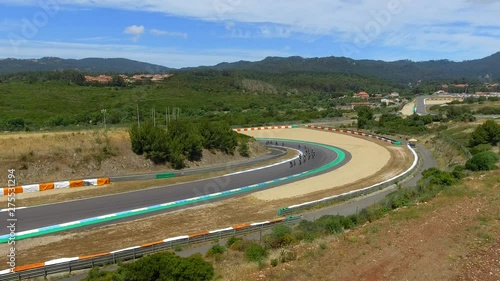 Aerial, descending, drone shot, of a group of cyclists, racing in a turn, on Estoril Circuit, at the 24h bike race, on a sunny day, near Lisbon, Portugal