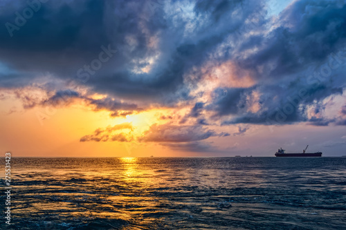 Sun appearing behind the stormy clouds over rough Atlantic ocean waves. © Igor Groshev