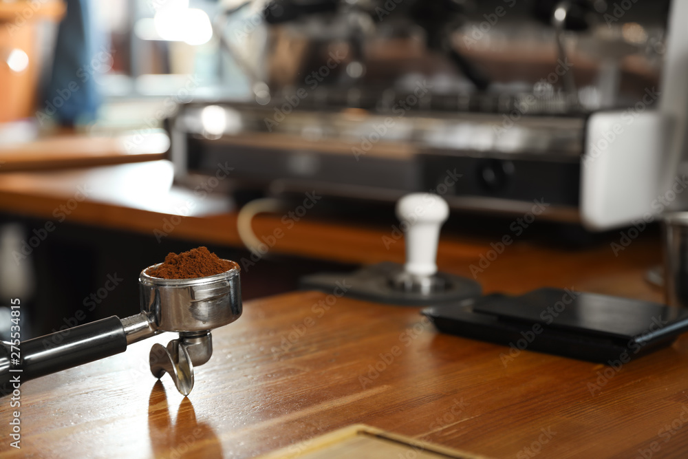 Portafilter with milled coffee on counter in bar. Space for text