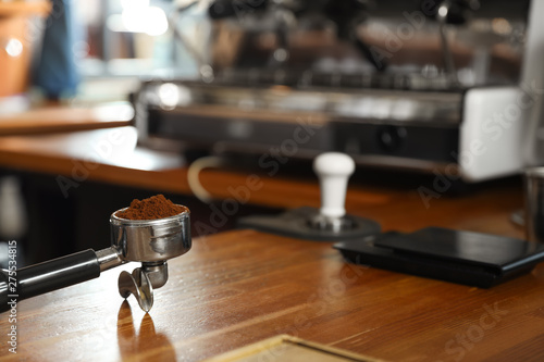 Portafilter with milled coffee on counter in bar. Space for text