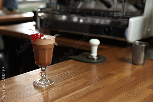 Glass of coffee drink with cherry and marshmallow on bar counter. Space for text