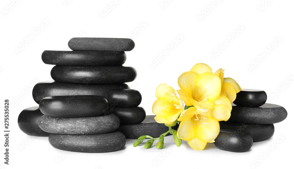 Stack of black spa stones and fresh flowers isolated on white