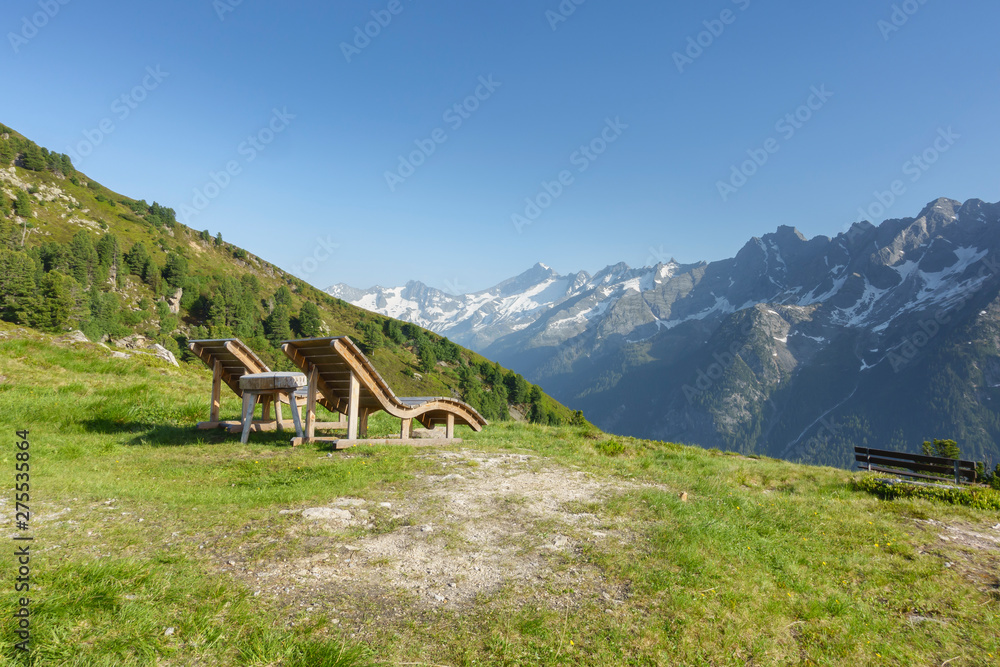 Liegestühle aus Holz mit Aussicht über die Alpen