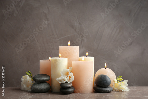 Photography Beautiful composition with candles, stones and flowers on table against grey bac