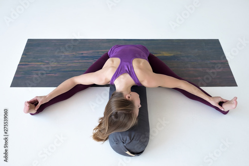 Caucasian woman doing youga splits upavistha konasana on fitness mat. Full length studio shot photo