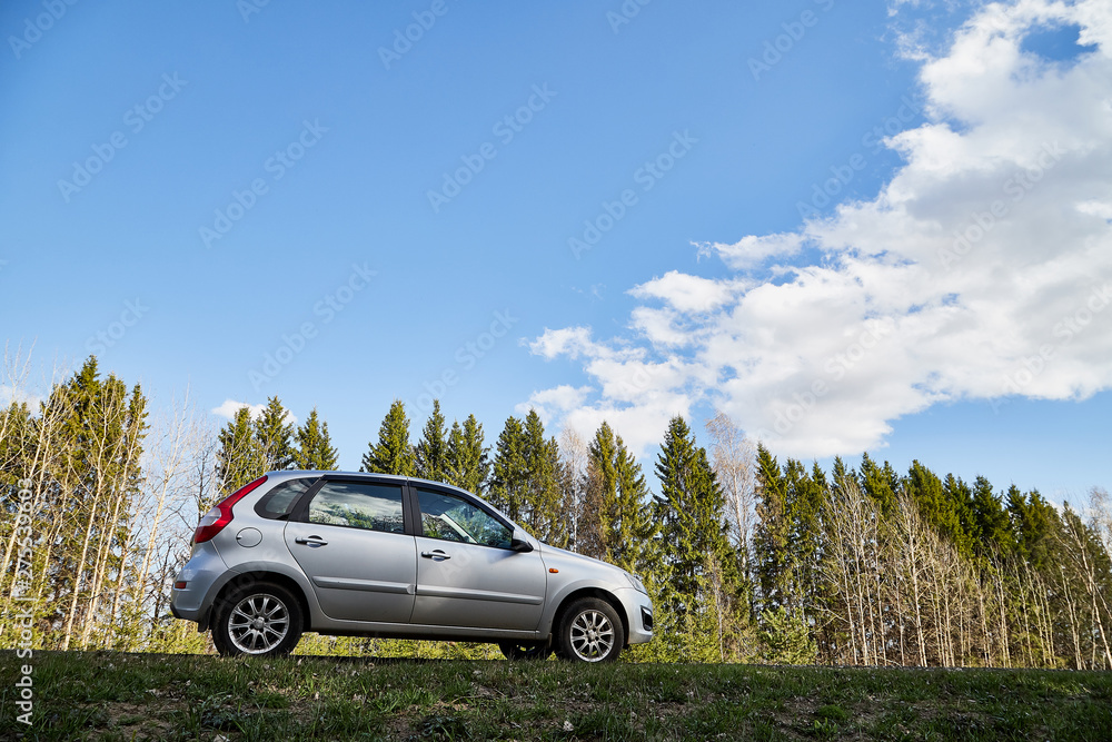 Car on asphalt road in early spring near forest and blue sky with clouds. Landscape in in nice spring day. Russia