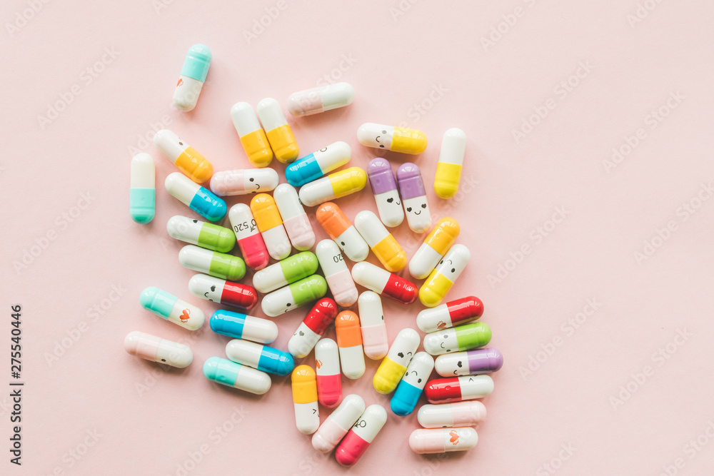 Pile of funny colored capsule on a pastel paper pink background. Pile of funny colored capsule on a pastel paper pink background.