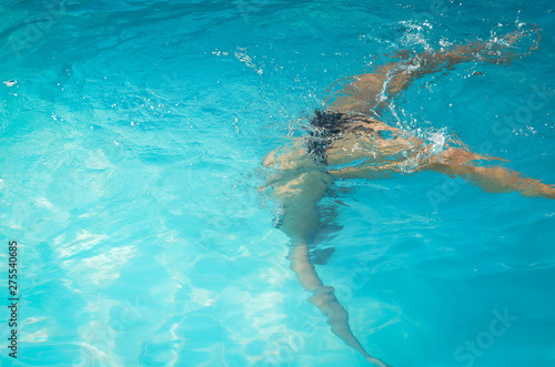 Young woman swimming underwater in swimming pool.
