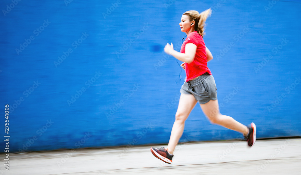 blurred image of woman jogging in a red shirt against blue background - healthy lifestyle blurred image of woman jogging in a red shirt against blue background - healthy lifestyle