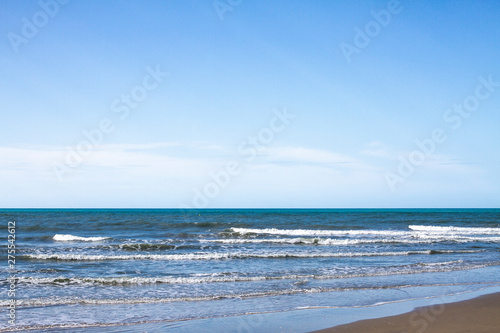  Beach with breaking waves and blue sky.