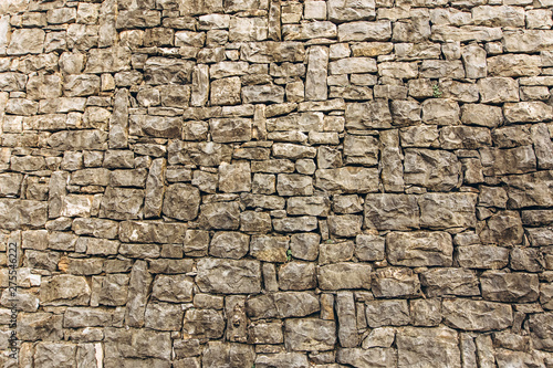 Old stone wall on background. Brick wall with ancient masonry. Full frame of rich and varied texture. A fragment of the old wall of natural stone.