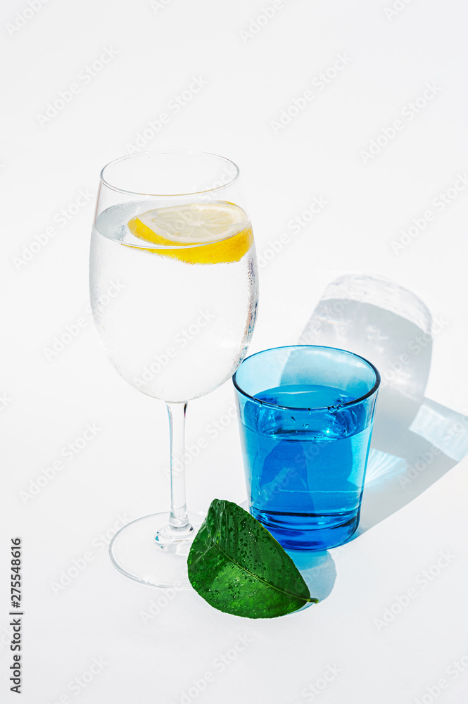 Wet glass with water and lemon. Hot weather drink. Healthy organic food background. Bright minimalistic clean photo. Sun light illumination. Vitamin C body nutrition element. Wet glass with water and lemon. Hot weather drink. Healthy organic food background. Bright minimalistic clean photo. Sun light illumination. Vitamin C body nutrition element.
