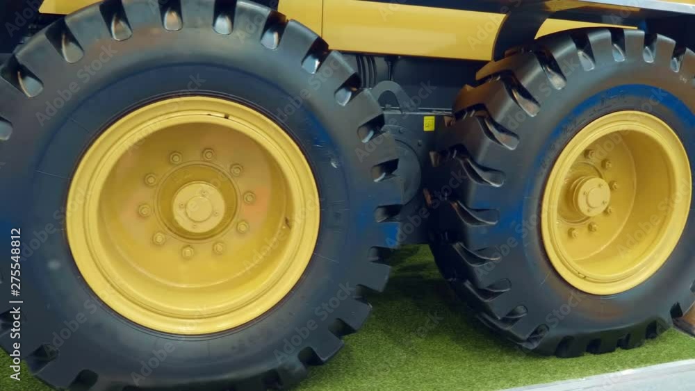Big new wheels with yellow rims on a construction grader. A new sample is presented for review at the exhibition. Shot in motion Big new wheels with yellow rims on a construction grader. A new sample is presented for review at the exhibition. Shot in motion