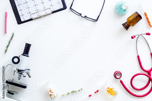 Doctors desk in laboratory with microscope, stethoscope, cardiogram frame for research white background top view mock up