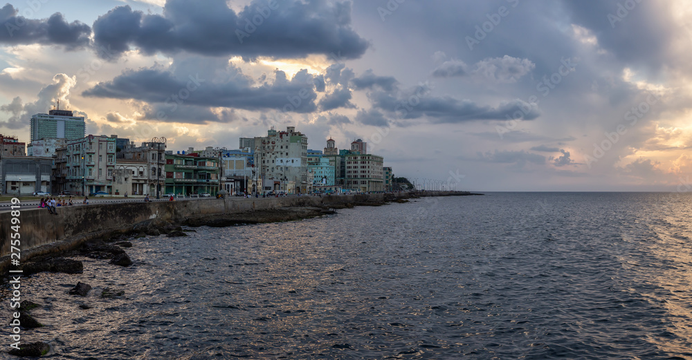 Panoramic view of the Old Havana City, Capital of Cuba, by the ocean coast during a dramatic cloudy sunset.