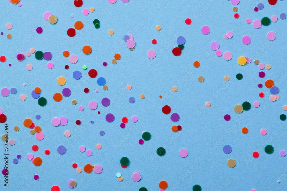 Multicolored round sequins on a pastel blue background with confetti.