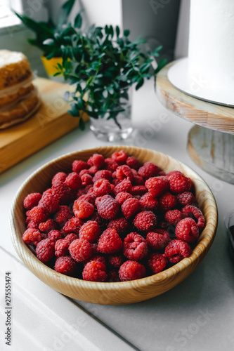 Ripe raspberries in a wooden plate on the table