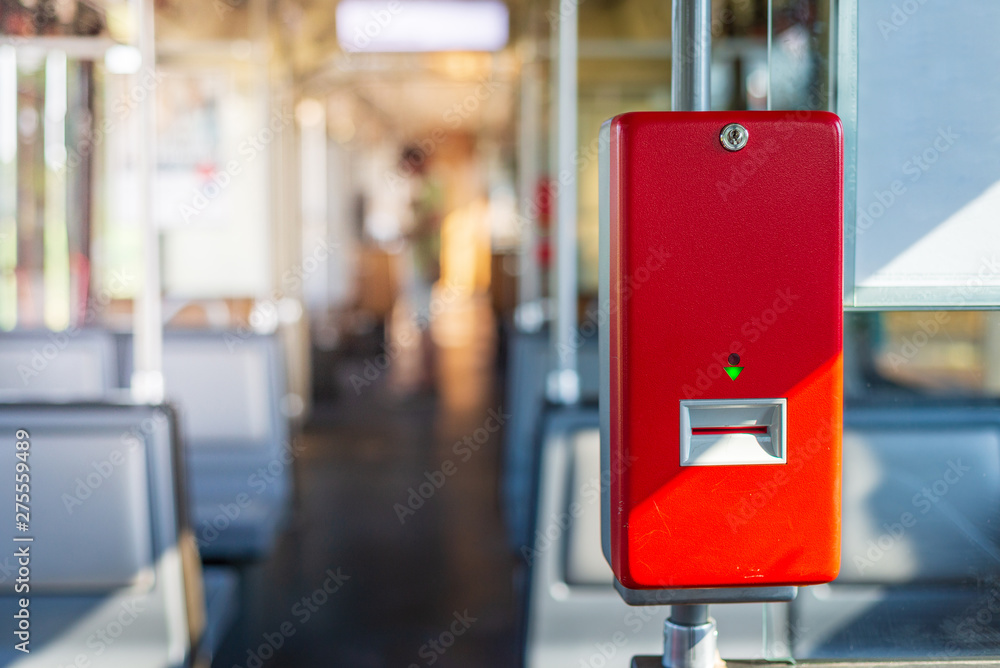 Selected focus of Red public transportation ticket stamp or validation ticket machine inside tram's passenger car without people of railway system in Rhein-Ruhr region in Düsseldorf, Germany. Selected focus of Red public transportation ticket stamp or validation ticket machine inside tram's passenger car without people of railway system in Rhein-Ruhr region in Düsseldorf, Germany.