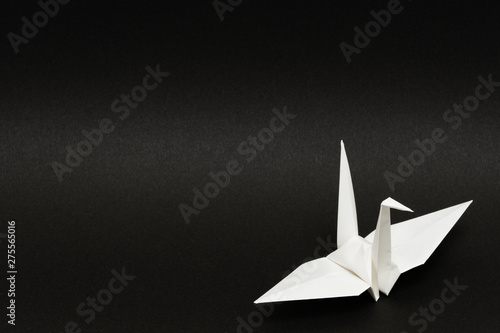 white origami paper crane on black background