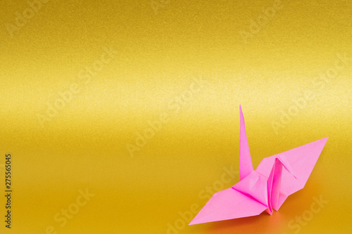 pink origami paper crane on golden background