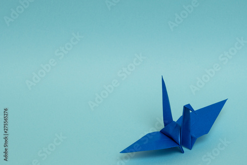 blue origami paper crane on sky blue background