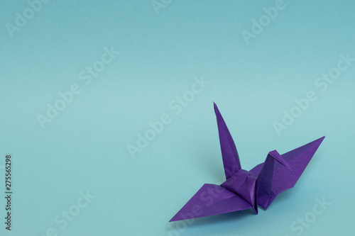 purple origami paper crane on sky blue background
