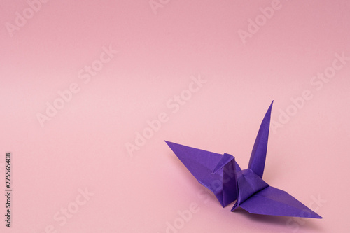 purple origami paper crane on pink background